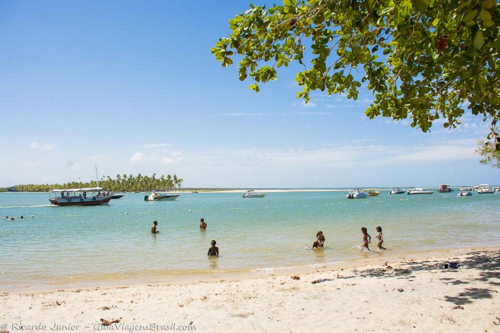 Imagem de crianças brincando nas águas da Praia da Boca da Barra.